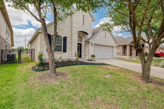 french country inspired facade featuring driveway, stone siding, fence, an attached garage, and a front yard