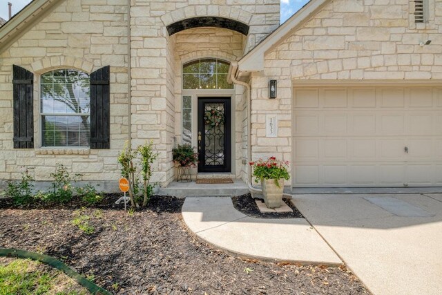 entrance to property with stone siding, driveway, and a garage