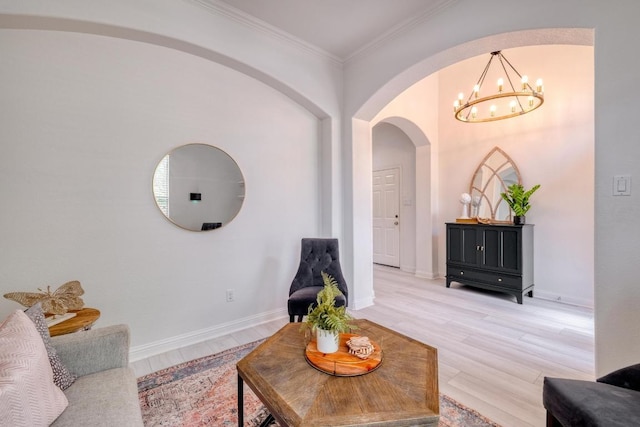 living area featuring arched walkways, ornamental molding, light wood finished floors, and an inviting chandelier