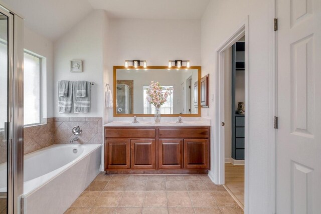 full bathroom with a bath, a sink, double vanity, and a stall shower
