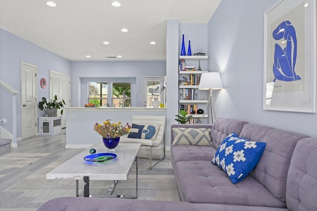 living area with recessed lighting, wood finished floors, visible vents, and stairs