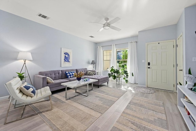 living area with ceiling fan, visible vents, and light wood-type flooring