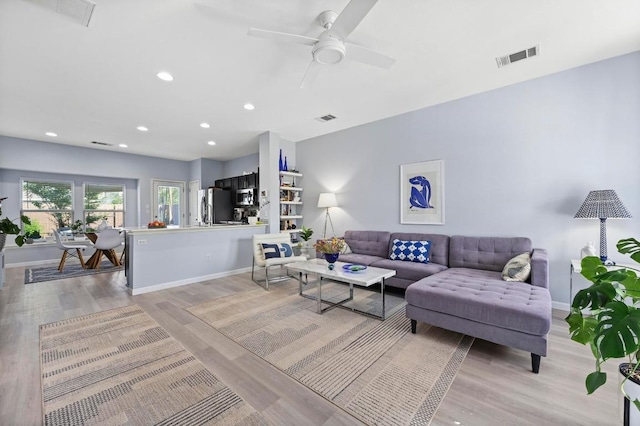 living room featuring light wood-style floors, visible vents, and baseboards