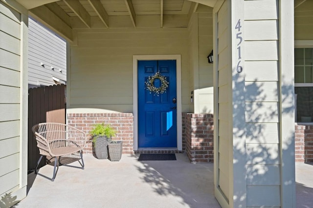 entrance to property with a porch and brick siding