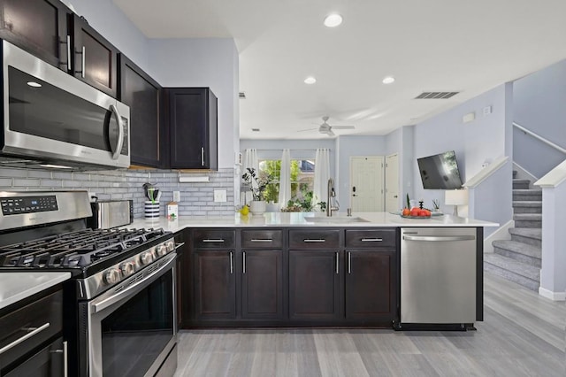 kitchen with stainless steel appliances, a sink, visible vents, light wood-style floors, and ceiling fan