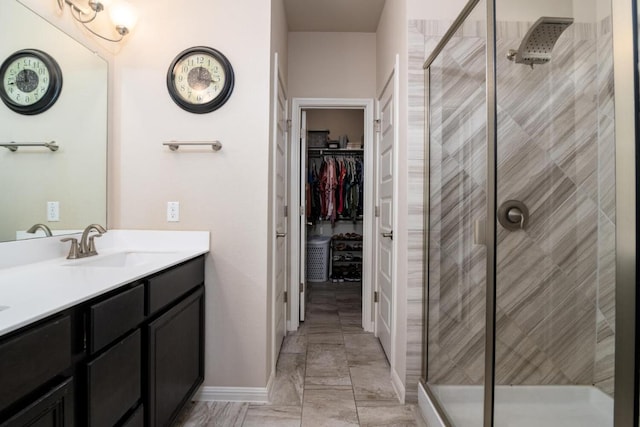 full bath featuring vanity, a spacious closet, marble finish floor, and a stall shower