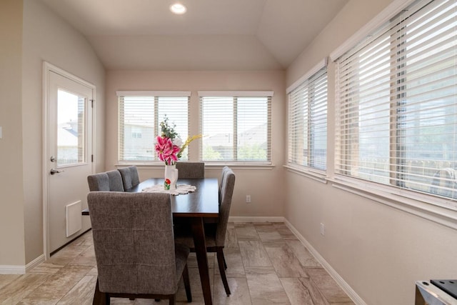 dining room with lofted ceiling, a healthy amount of sunlight, and baseboards