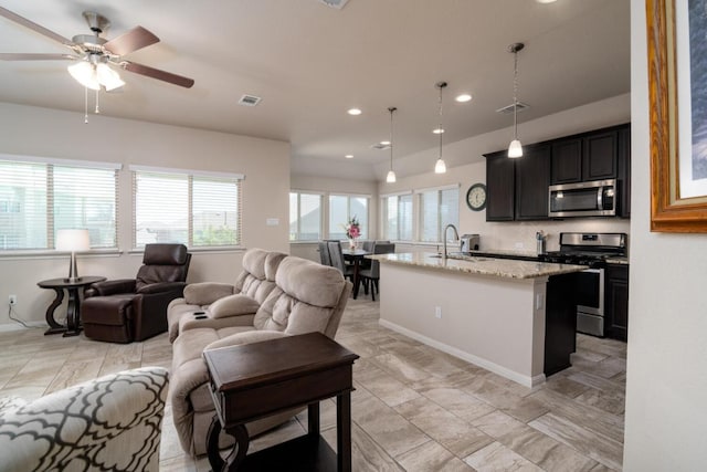 kitchen featuring stainless steel appliances, a kitchen island with sink, a sink, visible vents, and ceiling fan