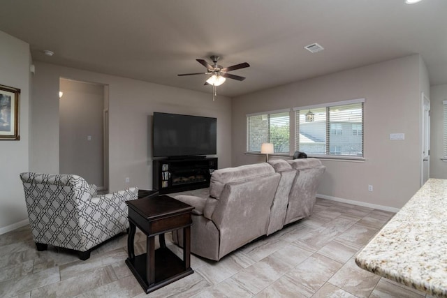 living area with baseboards, visible vents, and ceiling fan