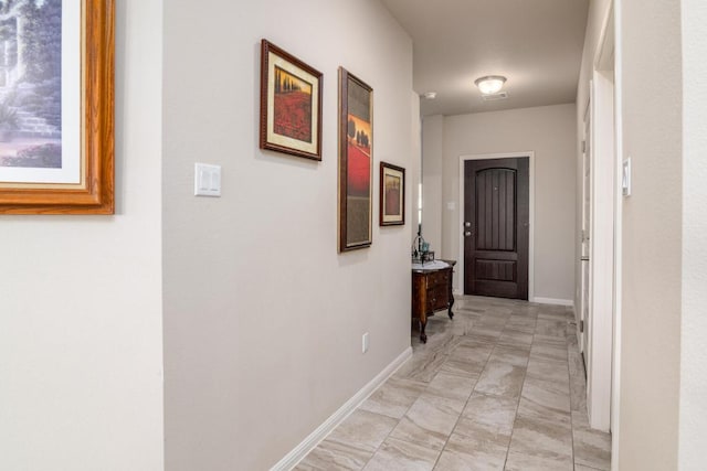 hallway with marble finish floor and baseboards