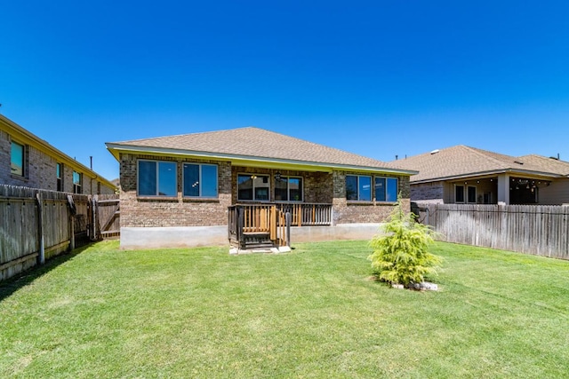 rear view of property with a fenced backyard, brick siding, and a yard