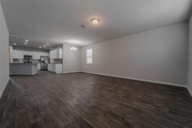 unfurnished living room featuring dark wood finished floors, baseboards, a notable chandelier, visible vents, and recessed lighting