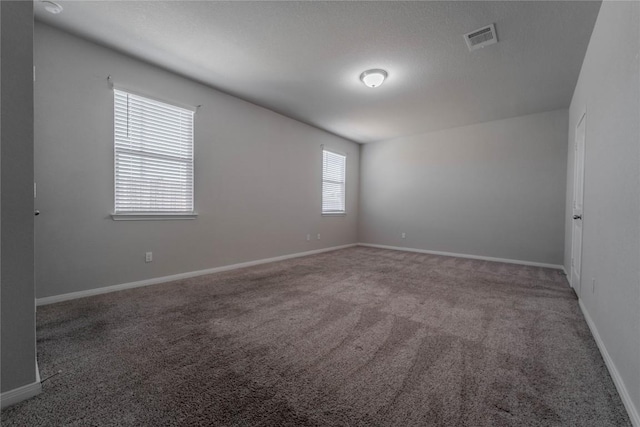 empty room featuring carpet floors, visible vents, and baseboards