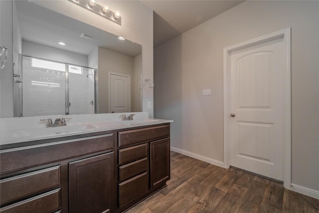 bathroom with a sink, double vanity, baseboards, wood finished floors, and a shower stall