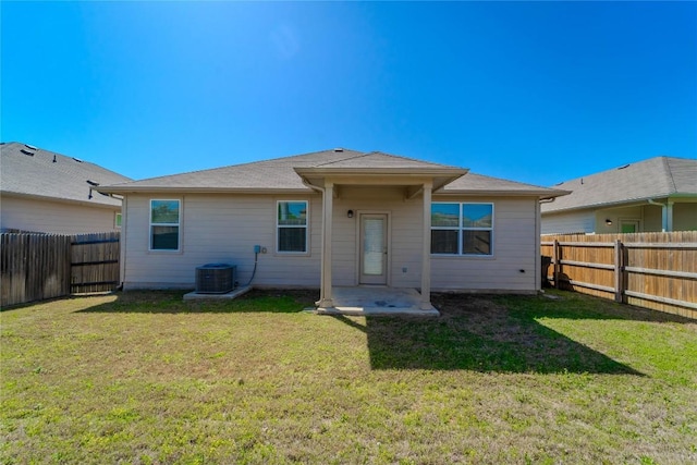 back of house with a fenced backyard, central AC unit, and a yard