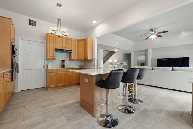 6659 Whitemarsh Valley Walk, Austin, TX 78746 - kitchen with black appliances, a breakfast bar area, light countertops, ceiling fan, and decorative backsplash