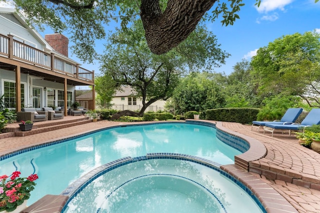 view of swimming pool featuring an outdoor living space, a pool with connected hot tub, a patio area, and a deck