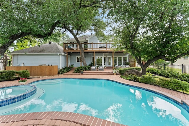 view of swimming pool featuring a deck, a pool with connected hot tub, fence, and a patio