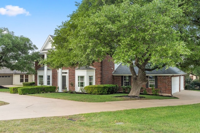 view of front of property featuring brick siding, a garage, a front yard, and concrete driveway
