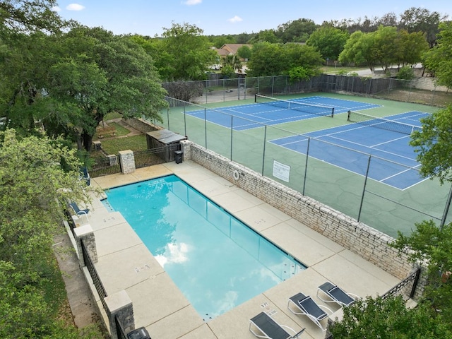 pool with fence and a tennis court
