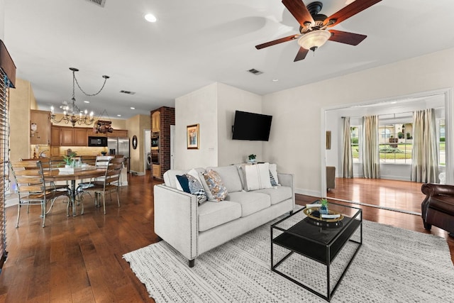 living room with visible vents, ceiling fan with notable chandelier, recessed lighting, and dark wood-type flooring