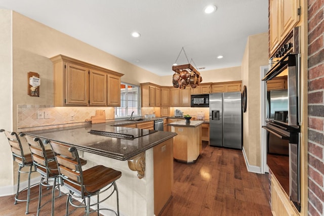 kitchen featuring a kitchen island, a peninsula, black appliances, and tasteful backsplash
