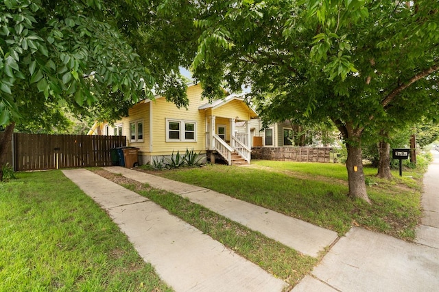 bungalow-style home featuring a gate, fence, driveway, and a front yard