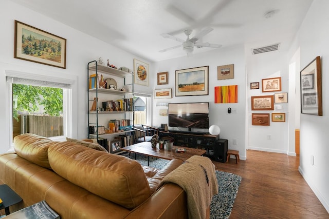 living area featuring baseboards, wood finished floors, visible vents, and ceiling fan