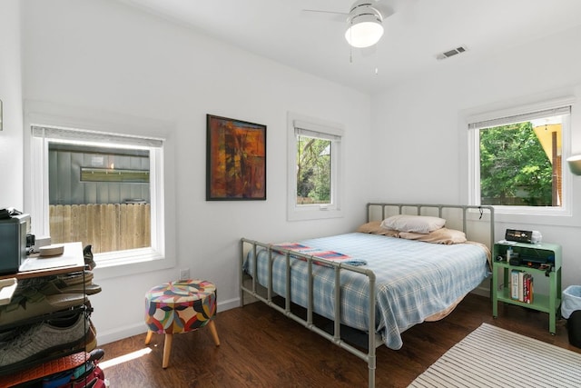 bedroom featuring wood finished floors, visible vents, baseboards, and multiple windows