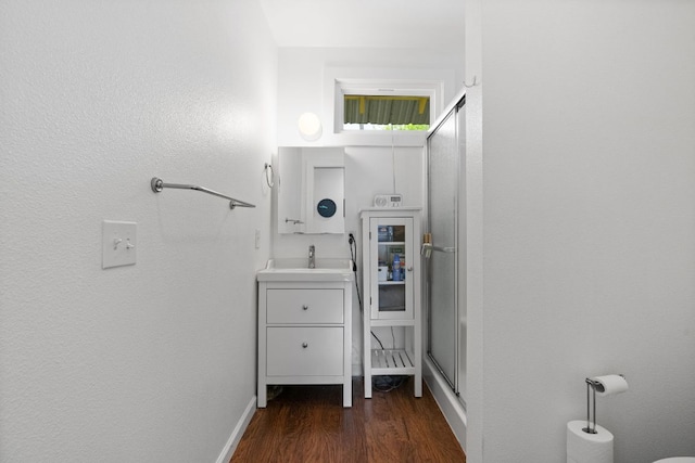 bathroom featuring baseboards, vanity, wood finished floors, and a stall shower