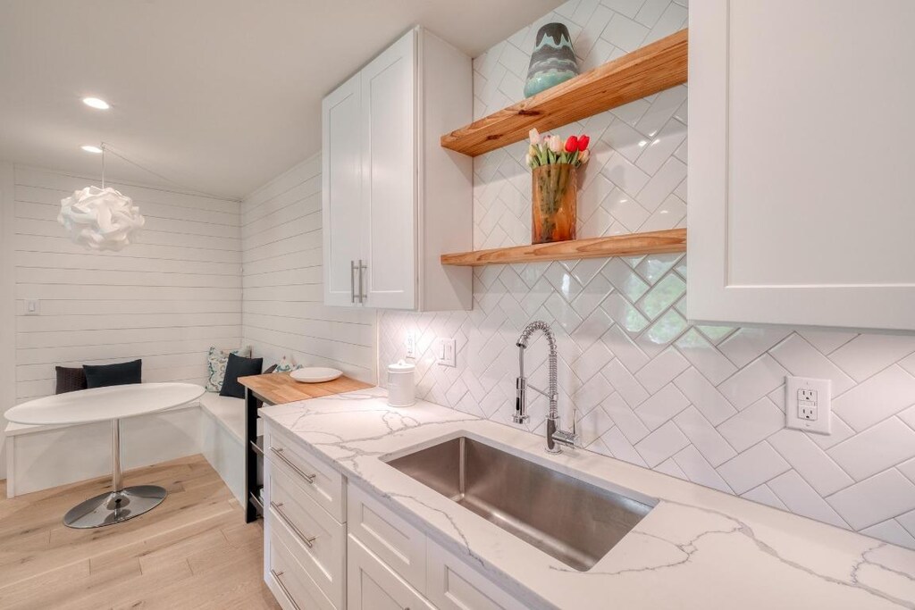 8210 Bent Tree Rd Unit 202, Austin, TX 78759 - kitchen featuring open shelves, a sink, light wood-style flooring, backsplash, and white cabinetry