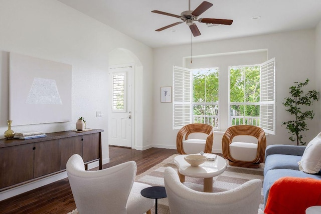 sitting room with dark wood-style flooring, baseboards, ceiling fan, arched walkways, and vaulted ceiling