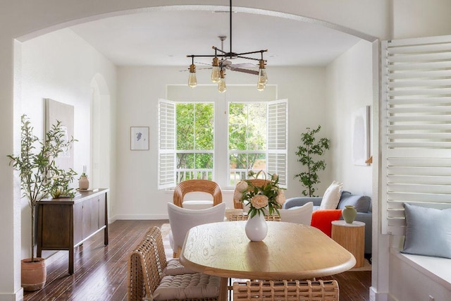 dining area with arched walkways, baseboards, a notable chandelier, and wood finished floors