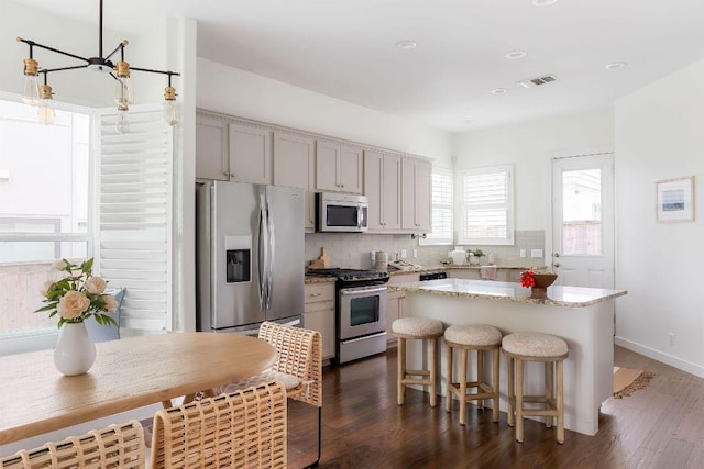 kitchen featuring a center island, dark wood-type flooring, tasteful backsplash, and stainless steel appliances
