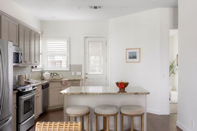 kitchen with visible vents, dark wood-style floors, a breakfast bar, and stainless steel appliances