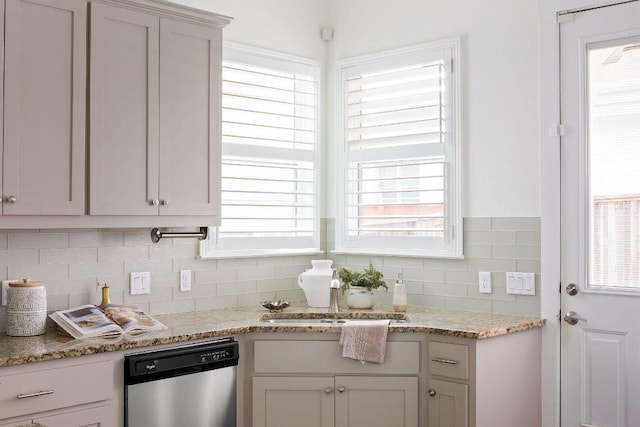 kitchen featuring light stone counters, backsplash, and dishwasher