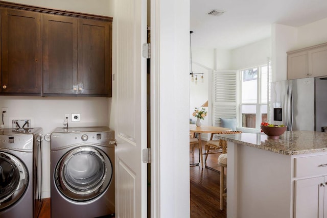 washroom featuring cabinet space, visible vents, washer and clothes dryer, and wood finished floors