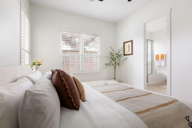 carpeted bedroom with baseboards, connected bathroom, and ceiling fan