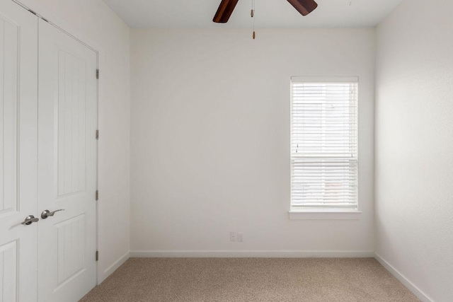unfurnished room featuring ceiling fan, light colored carpet, and baseboards