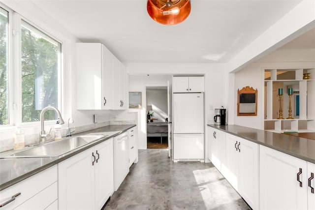 5323 Downs Dr, Austin, TX 78721 - kitchen featuring white appliances, a sink, dark countertops, white cabinetry, and finished concrete floors