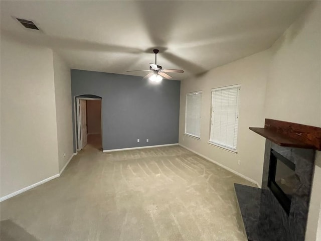 1709 Bush Coat Ln, Austin, TX 78754 - unfurnished living room with a glass covered fireplace, arched walkways, a ceiling fan, and light carpet