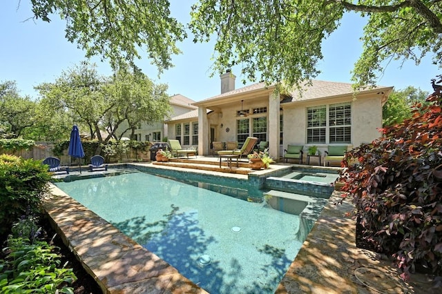 back of house featuring a chimney, fence, a pool with connected hot tub, a patio, and stucco siding