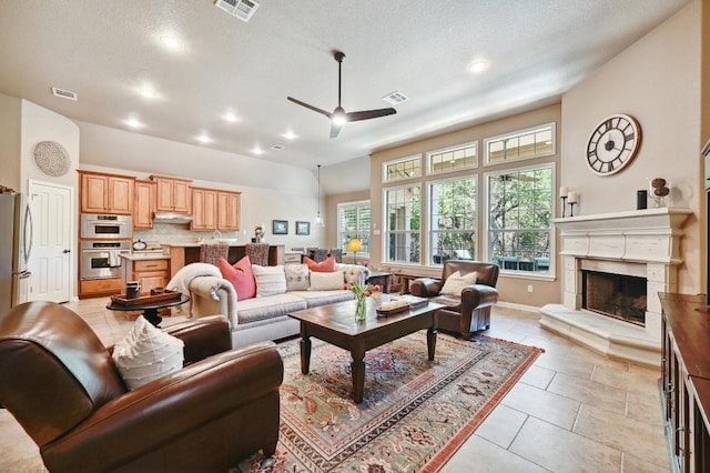 living area featuring a premium fireplace, visible vents, and a ceiling fan