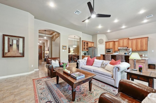 living room with arched walkways, a ceiling fan, visible vents, and baseboards