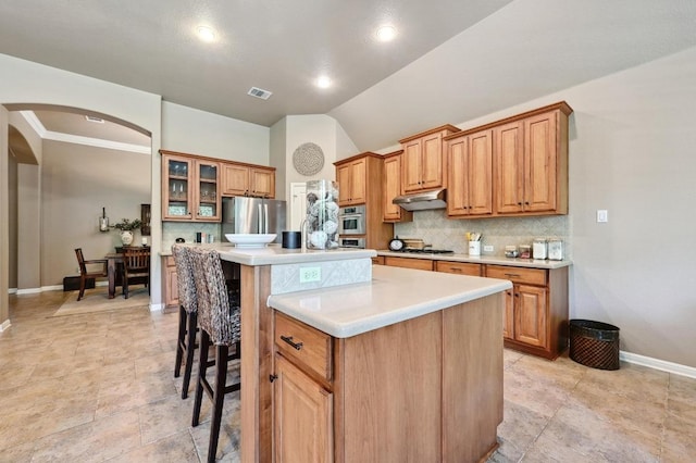 kitchen featuring a center island, arched walkways, visible vents, decorative backsplash, and appliances with stainless steel finishes