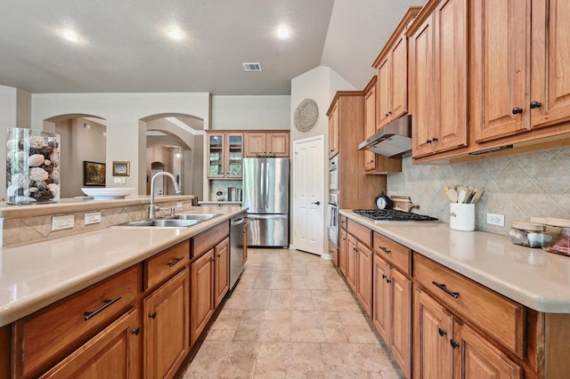 kitchen with stainless steel appliances, a sink, visible vents, decorative backsplash, and under cabinet range hood