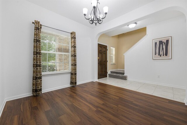 1812 Hidden Springs Path, Round Rock, TX 78665 - spare room featuring arched walkways, wood finished floors, a chandelier, stairway, and baseboards
