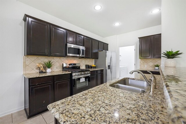 1812 Hidden Springs Path, Round Rock, TX 78665 - kitchen with appliances with stainless steel finishes, a sink, light stone countertops, dark brown cabinetry, and tasteful backsplash