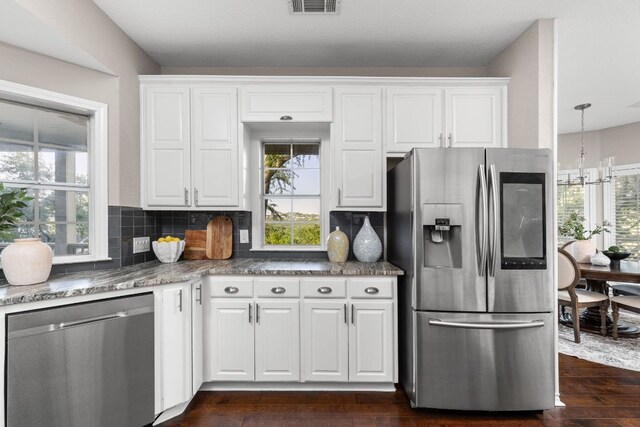 5710 Carry Back Ln, Austin, TX 78746 - kitchen with appliances with stainless steel finishes, white cabinets, dark wood-type flooring, and backsplash