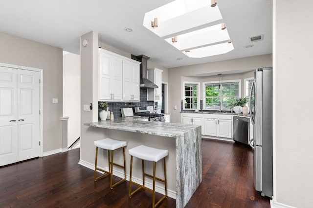 5710 Carry Back Ln, Austin, TX 78746 - kitchen featuring stainless steel appliances, a peninsula, dark wood-style flooring, decorative backsplash, and white cabinets